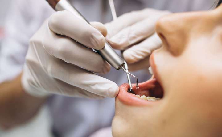 Dentista tratando os dentes de um paciente com instrumentos