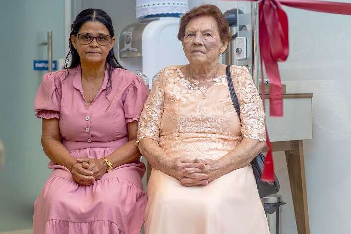 Duas mulheres sentadas lado a lado em sala do centro de saúde