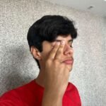 Jovem esfregando um dos olhos com a mão
