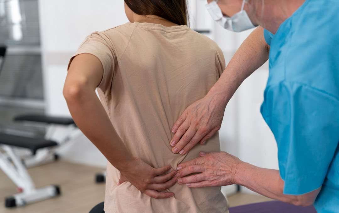 Fisioterapeuta examina a coluna lombar de uma paciente