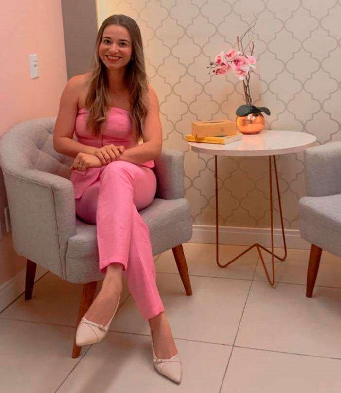Psicóloga Flávia Maria Santos sentada em poltrona no consultório