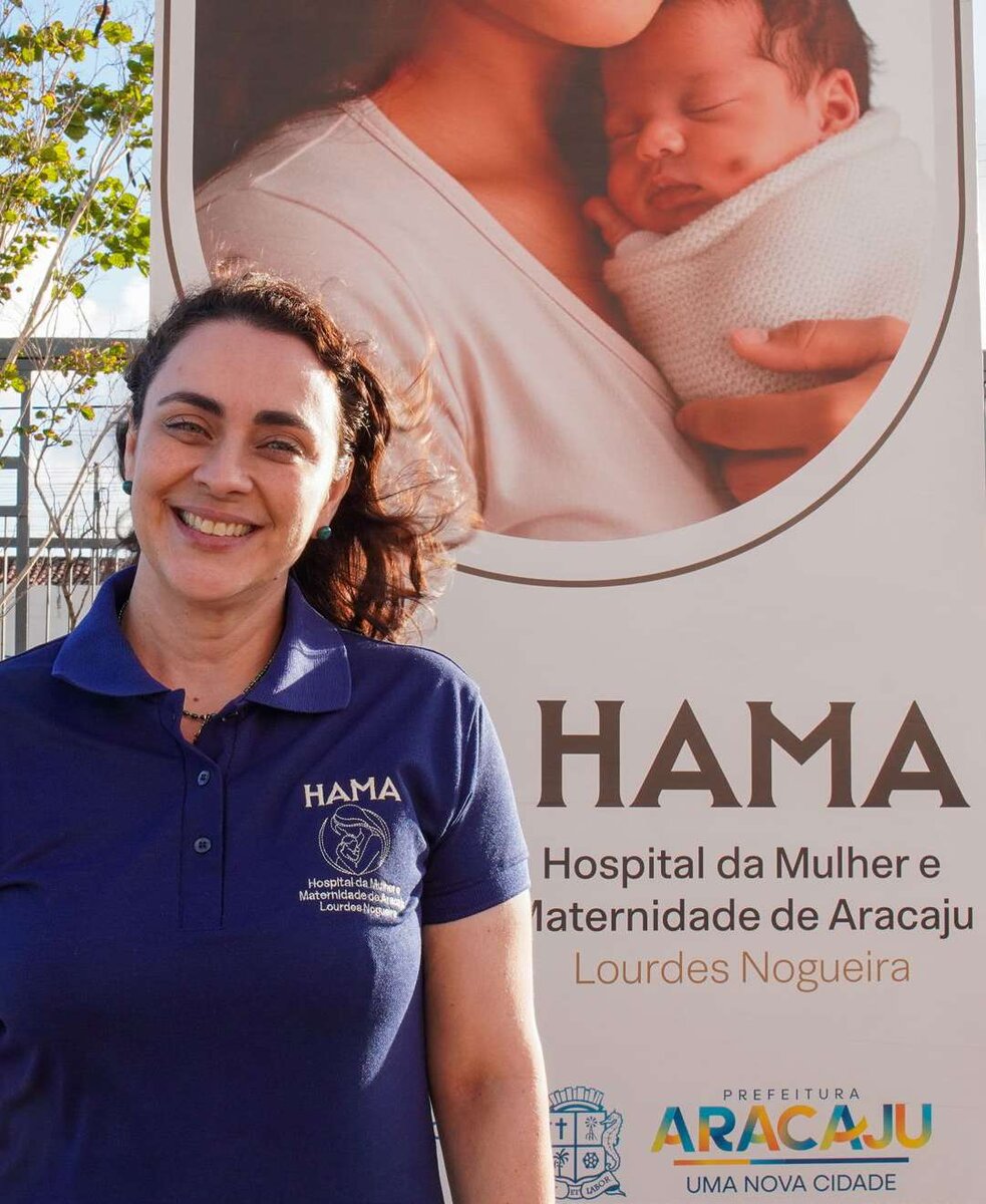 Mulher diante de painel do Hospital da Mulher e Maternidade de Aracaju