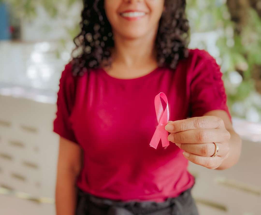 Mulher segura laço rosa do Outubro Rosa