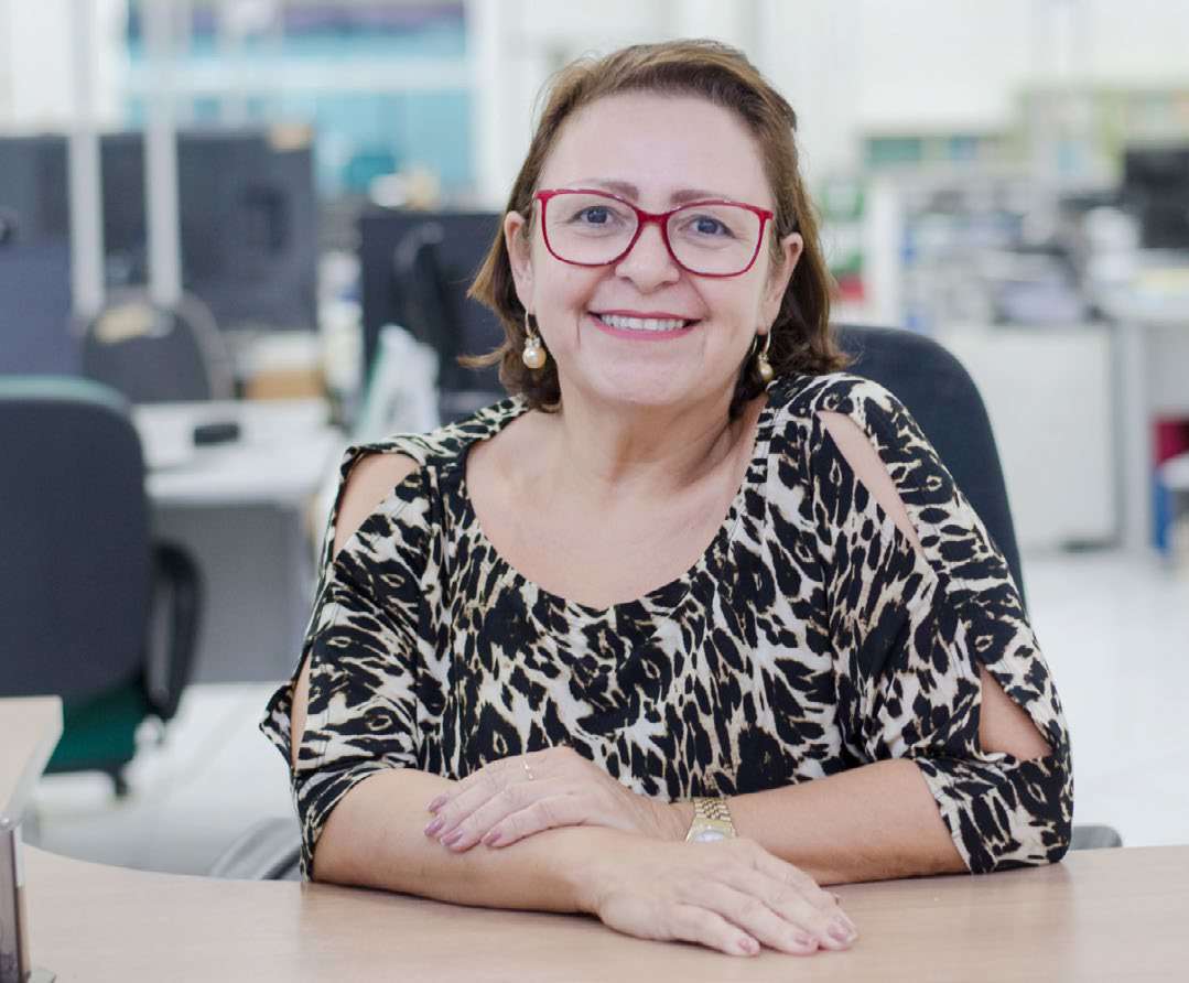 Iza Conceição Leó do Prado, a Izinha, sentada em escritório