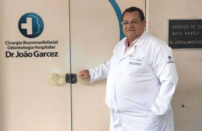 Dr. José Augusto Santos da Silva diante da placa do Serviço de Cirurgia Bucomaxilofacial