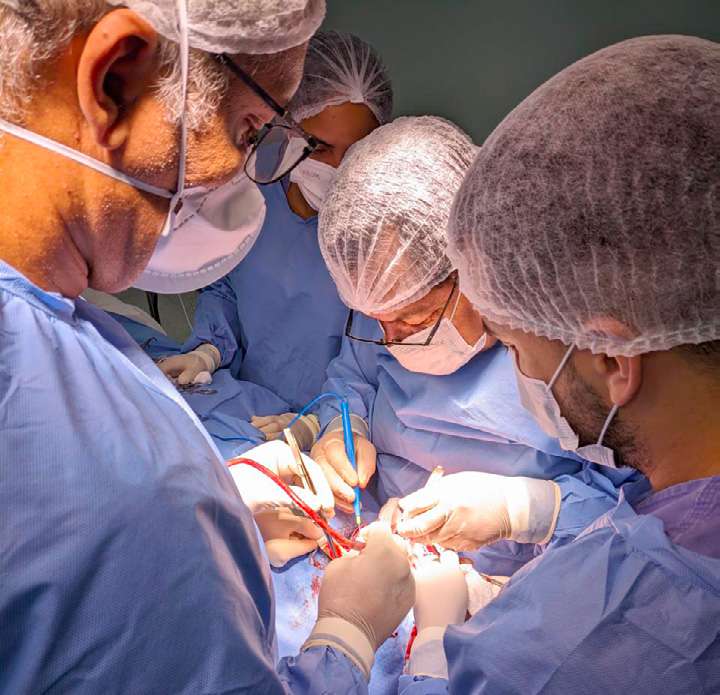 Equipe de cirurgiões com toucas e máscaras operando no centro cirúrgico