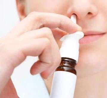 Pessoa aplicando spray de soro fisiológico no nariz