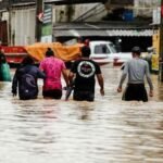 Pessoas caminhando em rua alagada
