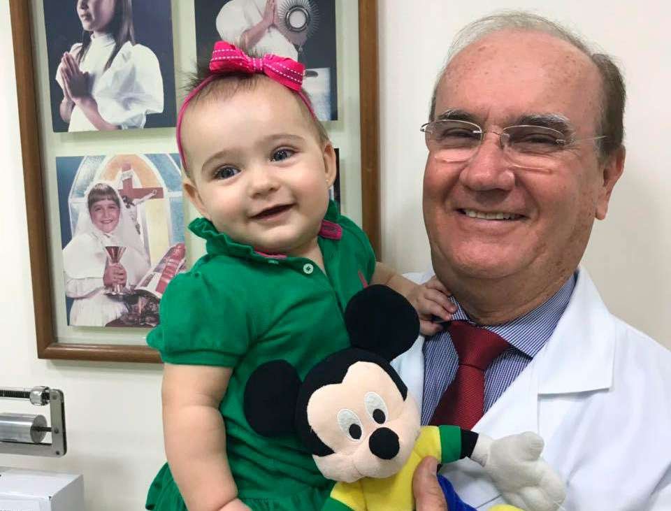 Pediatra Luciano Lima Franco com bebê no colo em consultório