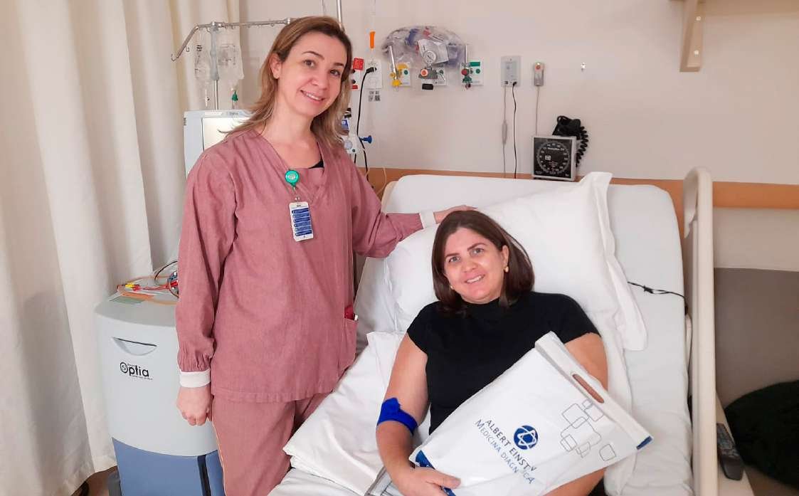 Marcelle Menezes Melo em leito hospitalar durante doação, ao lado de profissional de saúde