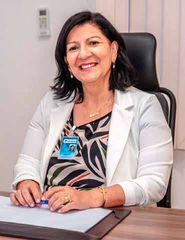 Márcia Guimarães sentada à mesa de trabalho, sorrindo