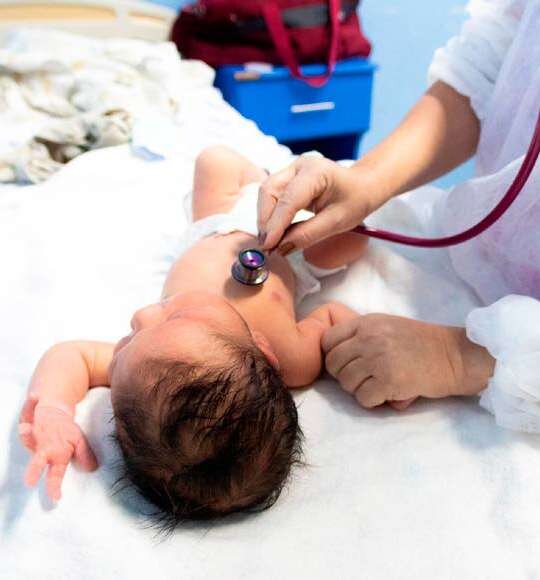 Profissional de saúde examina recém-nascido com estetoscópio