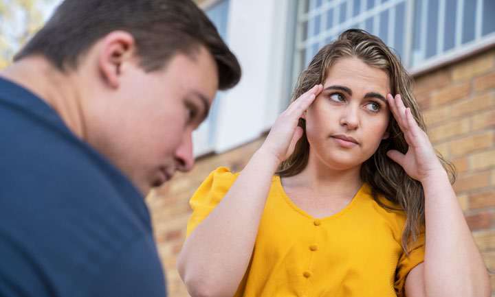Mulher com expressão de desconforto ao lado de homem