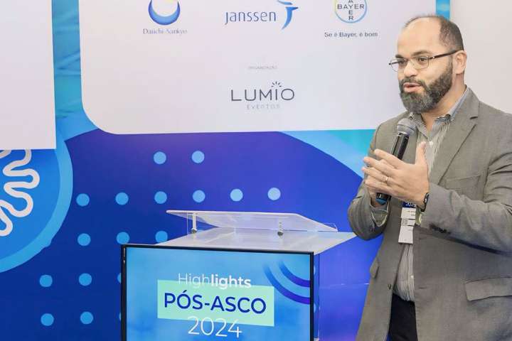 Dr. Nivaldo Farias fala ao microfone no Encontro Pós-ASCO 2024