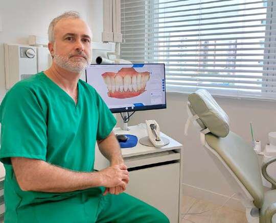 Dentista em consultório com imagem digital de prótese no monitor