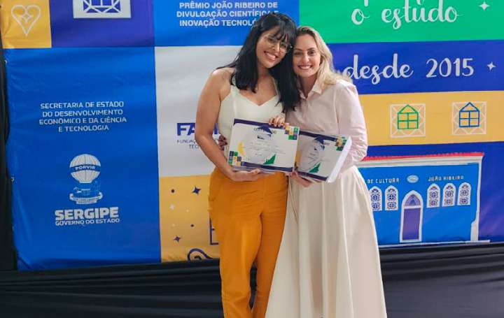 Estudante de Biomedicina e orientadora da Universidade Tiradentes segurando certificados