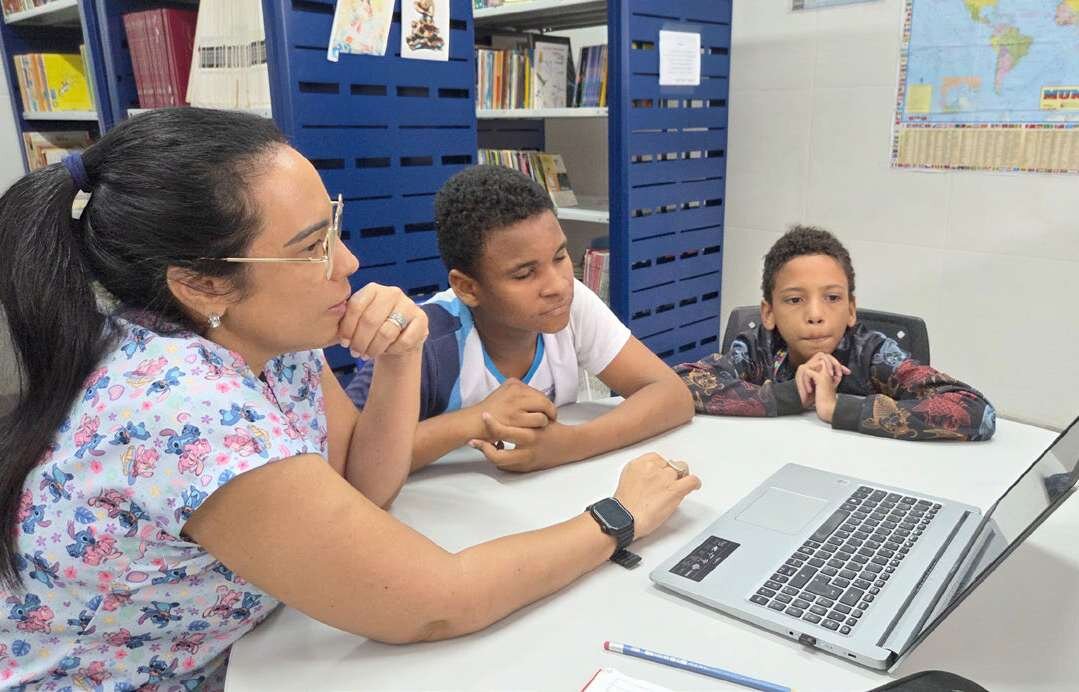 Profissional acompanha estudantes em atividade no computador