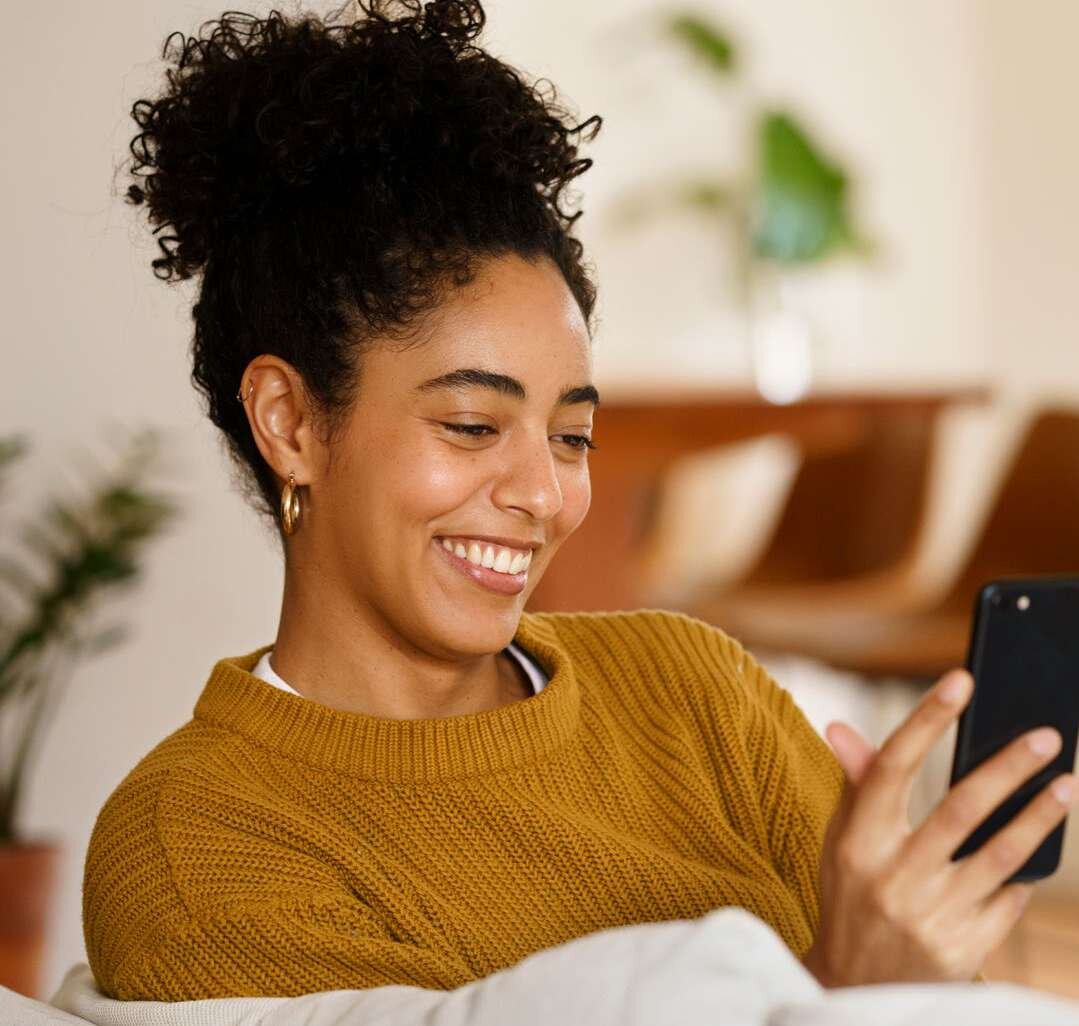 Mulher sorri enquanto olha o celular