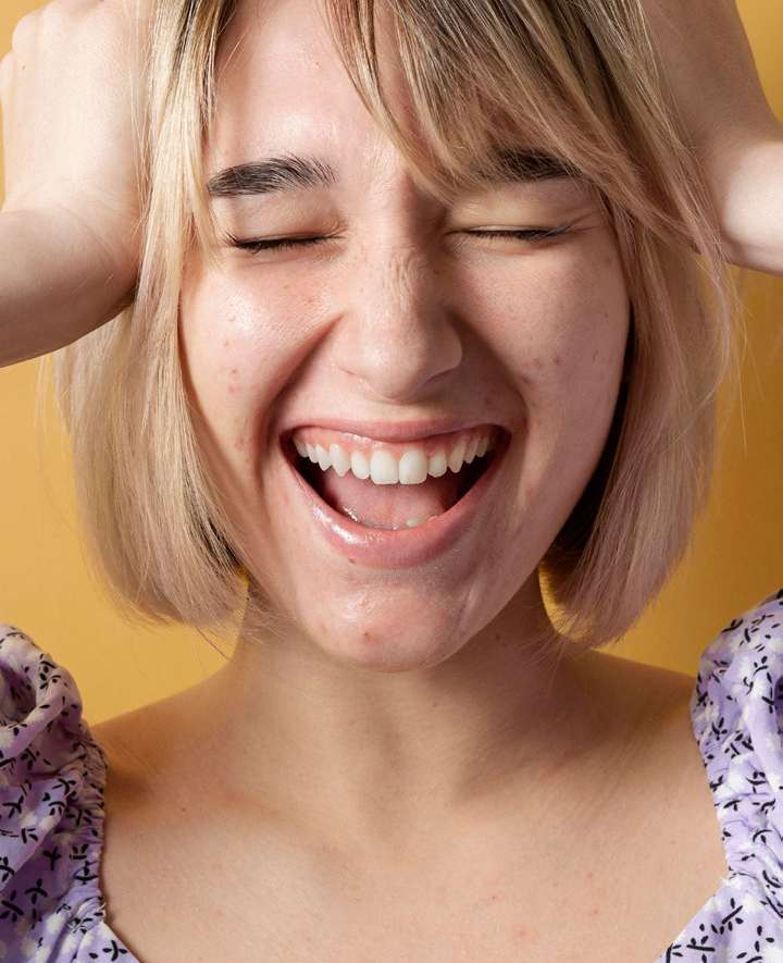 Mulher com expressão de dor levando as mãos à cabeça
