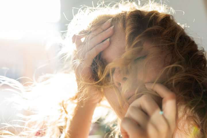 Mulher com expressão de angústia e a mão na cabeça