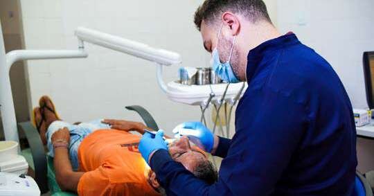 Dentista atende paciente em consultório odontológico de unidade de saúde