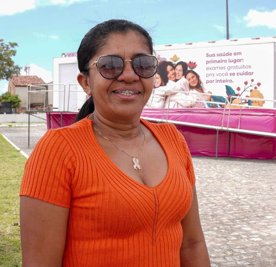 Mulher sorri diante da estrutura do Saúde Integrada da Mulher