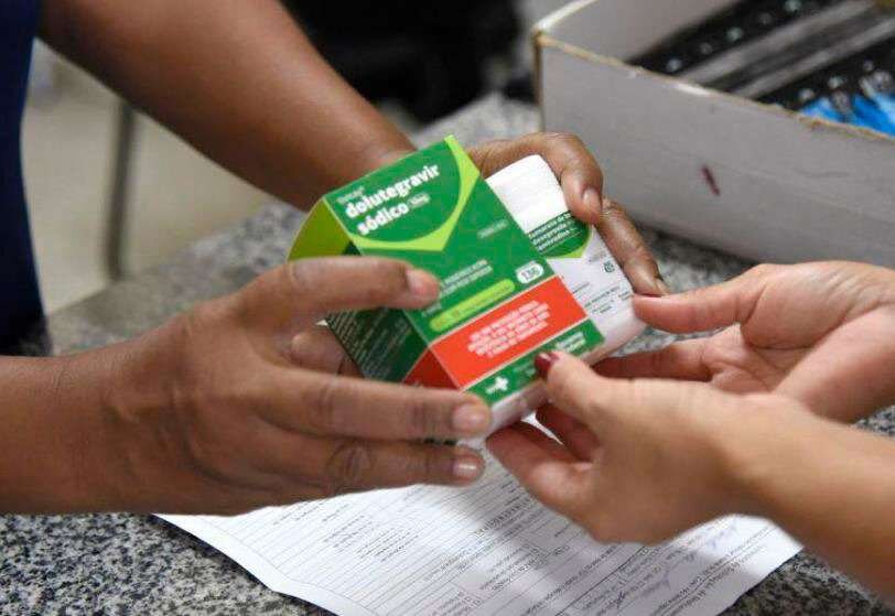Mãos entregam caixa de medicamento a usuário