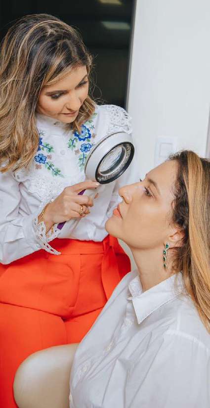 Dermatologista Thâmara Morita examina a pele de uma paciente com lupa