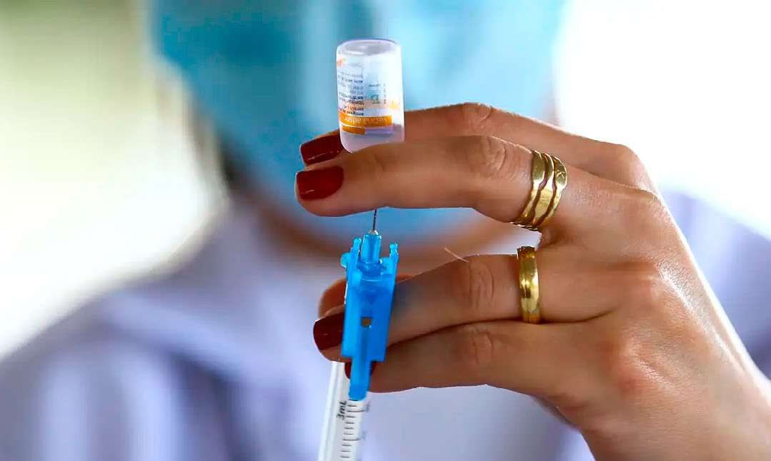 Profissional de saúde segura frasco de vacina e seringa