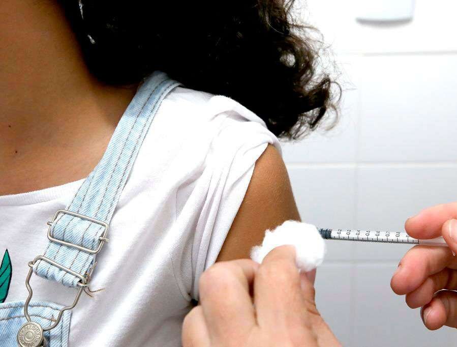 Profissional aplica vacina no braço de uma jovem